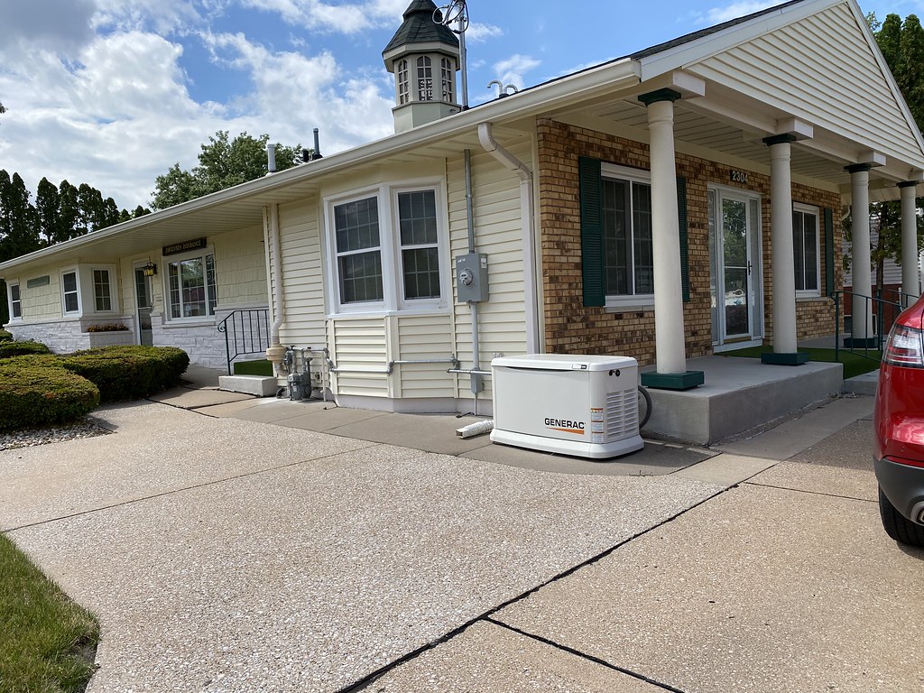 Standby generator installed on a concrete pad beside a house