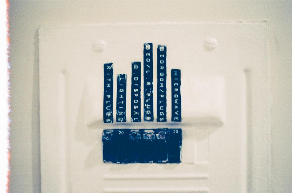 Older breaker panel painted over, with taped-on handwritten circuit labels