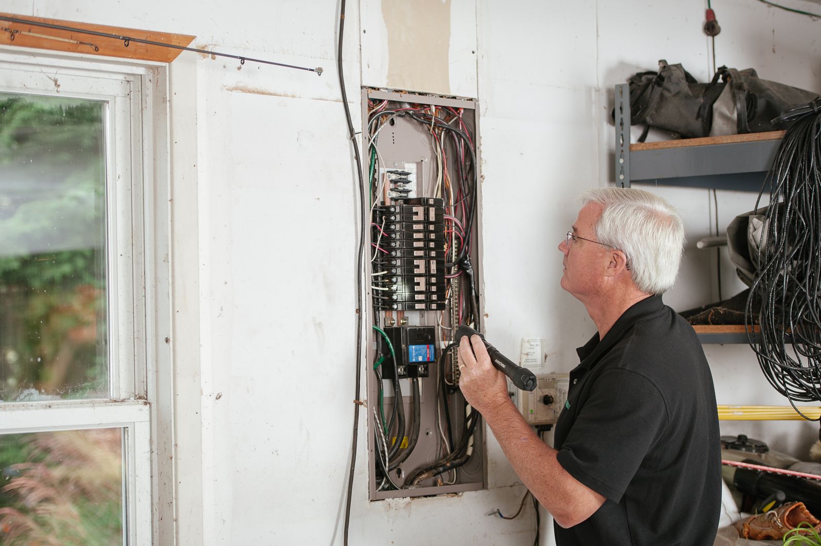Electrician checking an open residential breaker panel before writing a quote